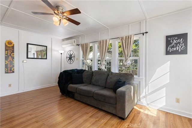 living room featuring ceiling fan, hardwood / wood-style floors, and a wall unit AC