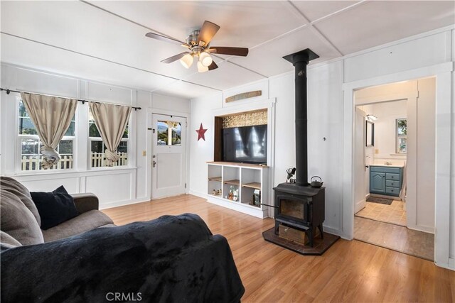 living room featuring hardwood / wood-style flooring, a wood stove, and ceiling fan