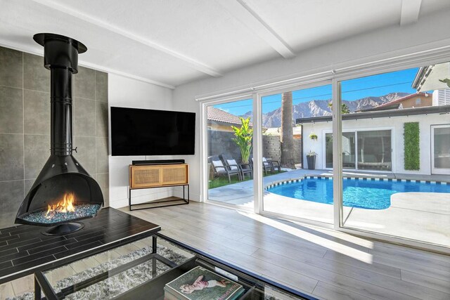 living room with beamed ceiling, a wood stove, and hardwood / wood-style flooring