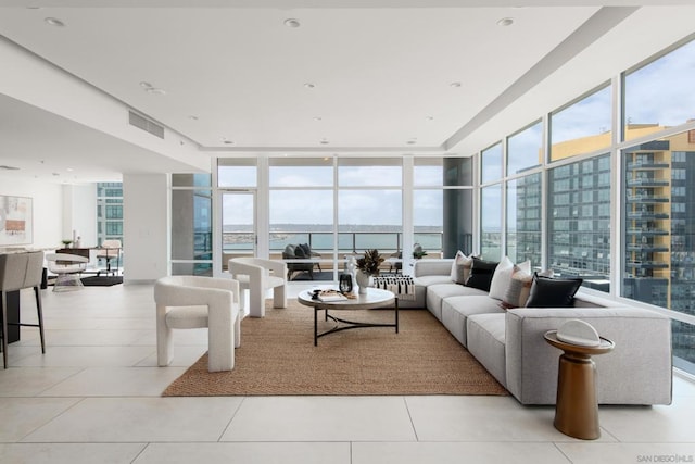 living room featuring light tile patterned floors, a wall of windows, and a water view