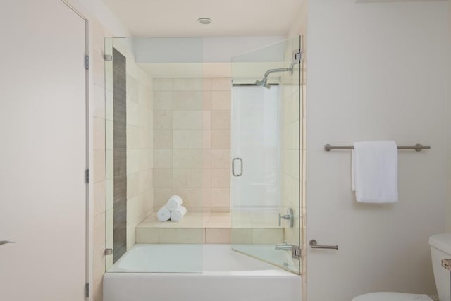 bathroom featuring toilet and combined bath / shower with glass door