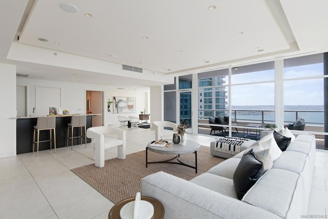 living room with a water view, light tile patterned flooring, and floor to ceiling windows