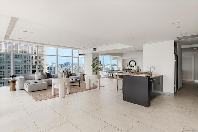 tiled living room with floor to ceiling windows, sink, and a tray ceiling