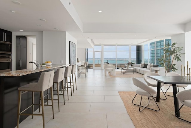 living room featuring floor to ceiling windows, light tile patterned flooring, and a water view