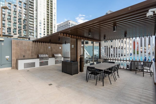 view of patio / terrace with exterior kitchen, a pergola, and grilling area