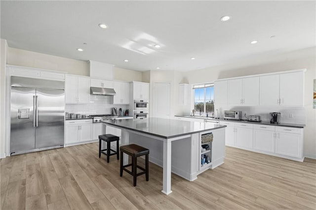 kitchen featuring a kitchen breakfast bar, white cabinetry, stainless steel appliances, and a kitchen island