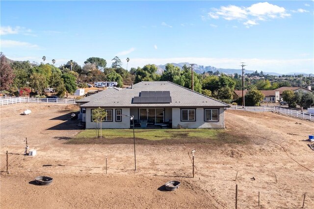 back of house with a mountain view and solar panels