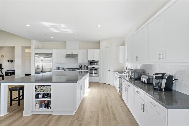 kitchen with a center island, white cabinetry, stainless steel appliances, tasteful backsplash, and sink