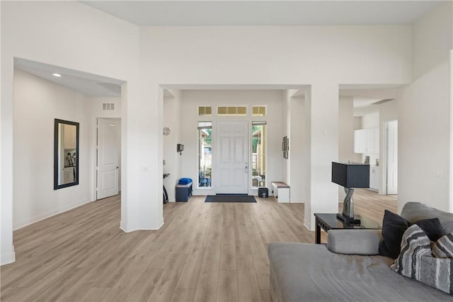 foyer entrance featuring light wood-type flooring and a towering ceiling