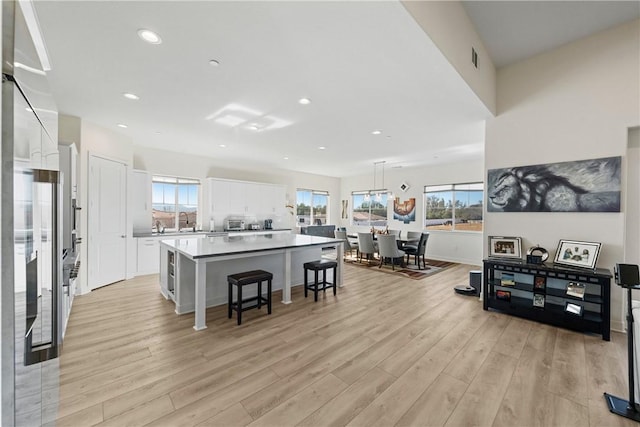 kitchen with pendant lighting, white cabinets, a center island, a kitchen bar, and light hardwood / wood-style flooring