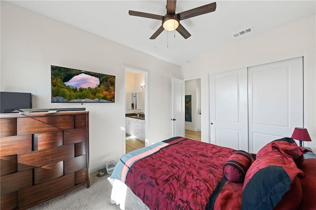 bedroom featuring ceiling fan, a closet, light carpet, and connected bathroom