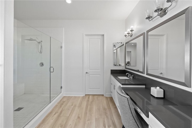 bathroom featuring hardwood / wood-style flooring, a shower with door, an inviting chandelier, and vanity