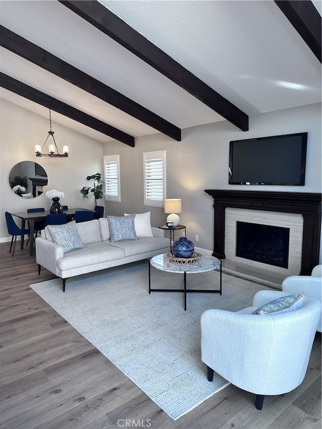 living room featuring vaulted ceiling with beams, a high end fireplace, a chandelier, and hardwood / wood-style floors