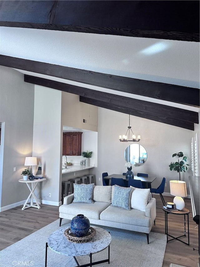 living room with sink, wood-type flooring, vaulted ceiling with beams, and an inviting chandelier