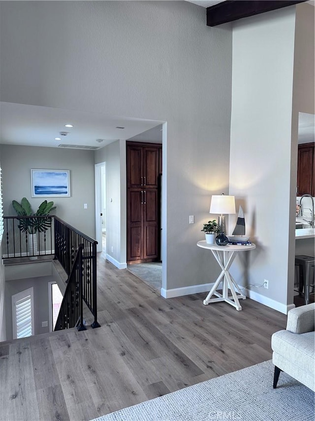 interior space with light wood-type flooring, sink, and beamed ceiling