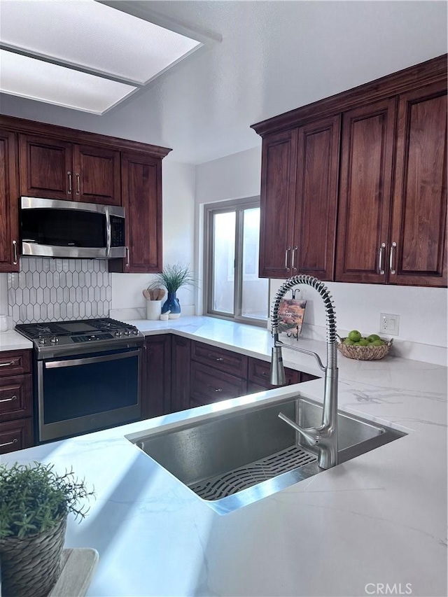 kitchen featuring appliances with stainless steel finishes, tasteful backsplash, and sink