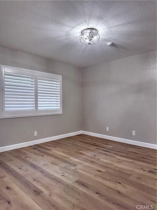 unfurnished room with a textured ceiling and hardwood / wood-style floors