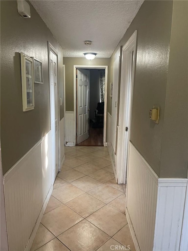 corridor with light tile patterned flooring and a textured ceiling