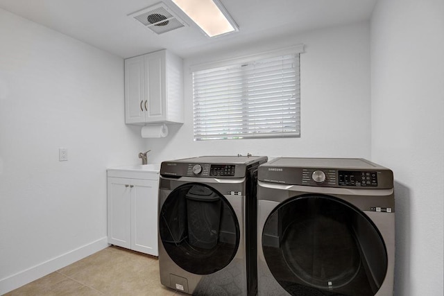 washroom featuring light tile patterned floors, sink, washer and clothes dryer, and cabinets