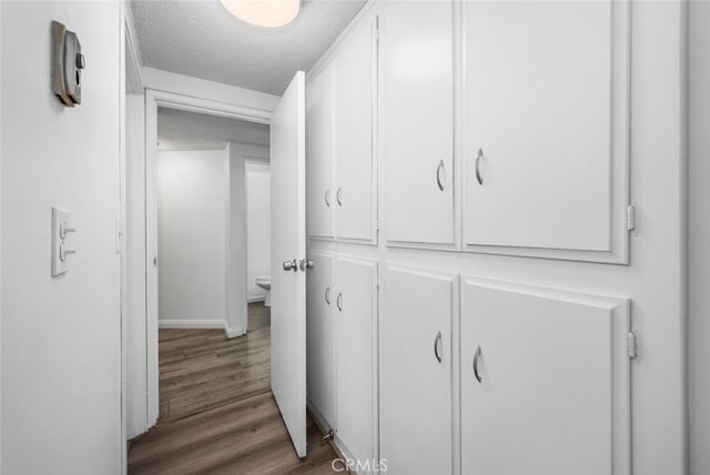 hallway featuring a textured ceiling and hardwood / wood-style flooring