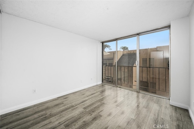 empty room featuring a wall of windows and hardwood / wood-style floors