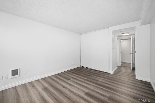 unfurnished bedroom featuring a closet, dark hardwood / wood-style flooring, and a textured ceiling