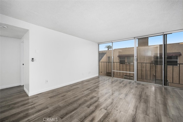 spare room with a textured ceiling, dark hardwood / wood-style flooring, and a healthy amount of sunlight