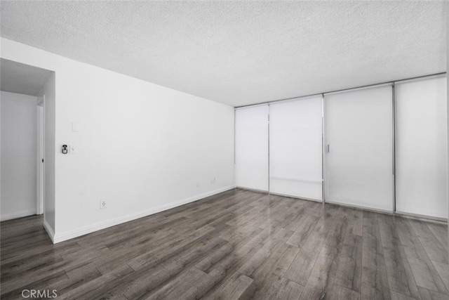 unfurnished bedroom with a textured ceiling, a closet, and dark hardwood / wood-style flooring