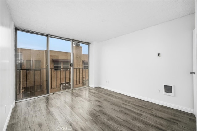 unfurnished room with wood-type flooring, floor to ceiling windows, and a textured ceiling