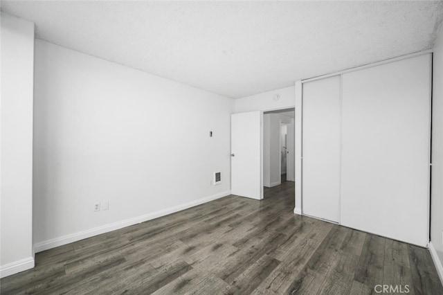 unfurnished bedroom with a closet and dark hardwood / wood-style floors