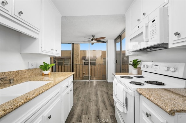 kitchen with light stone countertops, white appliances, white cabinets, dark hardwood / wood-style floors, and ceiling fan