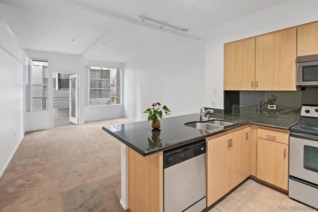 kitchen with dark stone countertops, light carpet, stainless steel appliances, kitchen peninsula, and sink