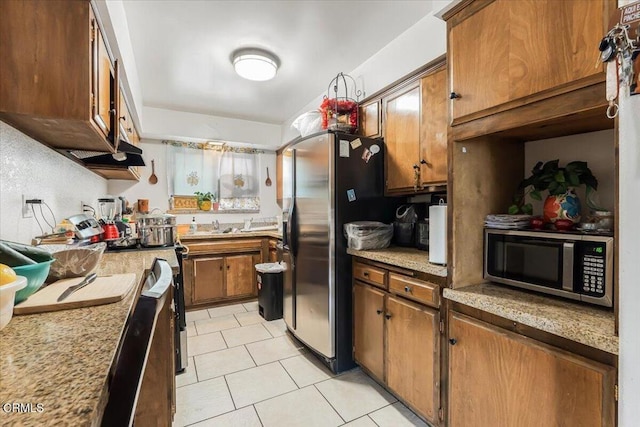 kitchen with light stone counters, light tile patterned floors, and appliances with stainless steel finishes