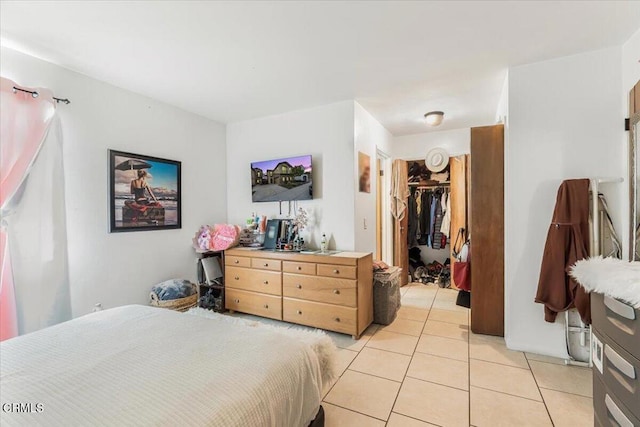 tiled bedroom featuring a spacious closet and a closet