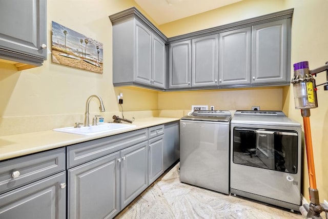 clothes washing area with sink, cabinets, and washing machine and clothes dryer