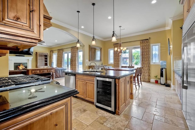 kitchen with a center island with sink, wine cooler, appliances with stainless steel finishes, crown molding, and decorative light fixtures