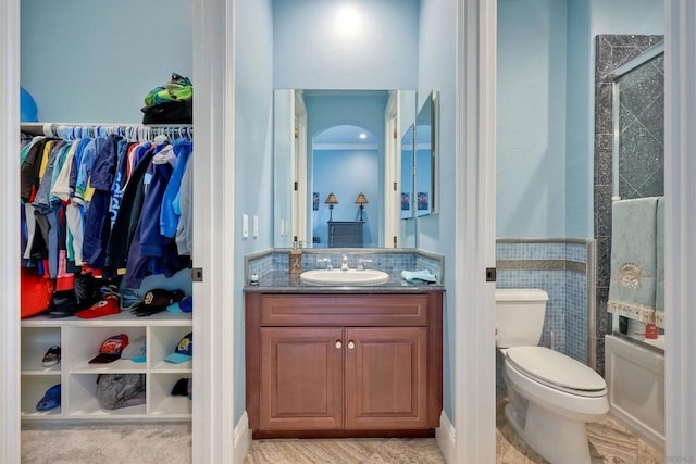 full bathroom featuring tile walls, enclosed tub / shower combo, vanity, and toilet