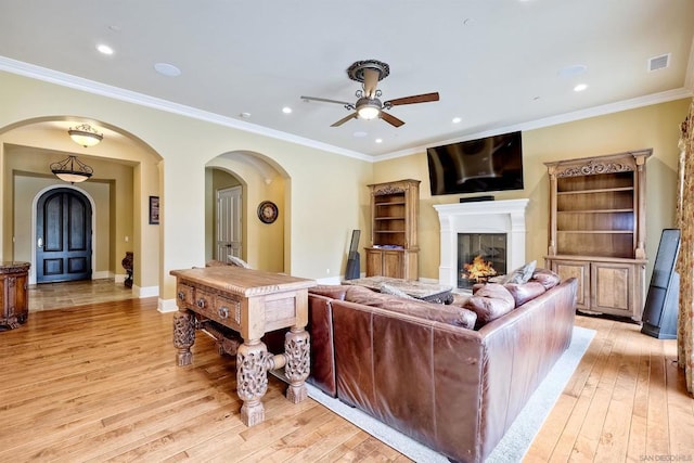 living room with ceiling fan, light wood-type flooring, and crown molding