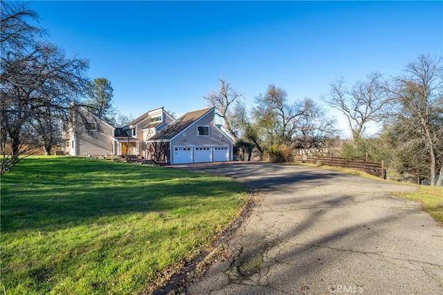 view of property exterior featuring a garage, a yard, aphalt driveway, and fence