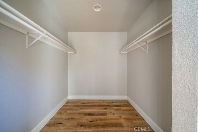 walk in closet with wood finished floors