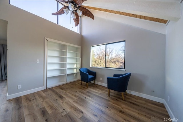 unfurnished room with hardwood / wood-style floors, beamed ceiling, built in features, high vaulted ceiling, and ceiling fan