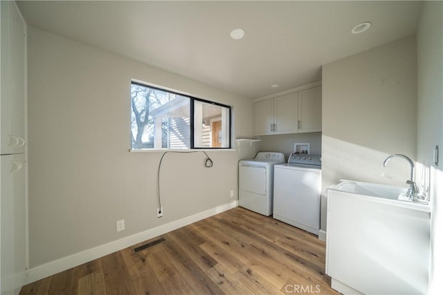 laundry area featuring visible vents, baseboards, cabinet space, light wood finished floors, and washer and clothes dryer