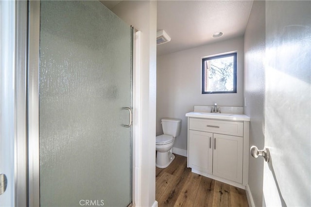 bathroom with hardwood / wood-style floors, toilet, walk in shower, and vanity