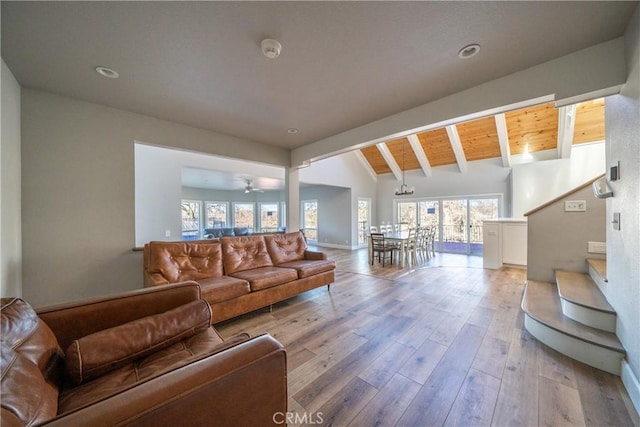 living room featuring ceiling fan, vaulted ceiling with beams, light wood-type flooring, and wooden ceiling