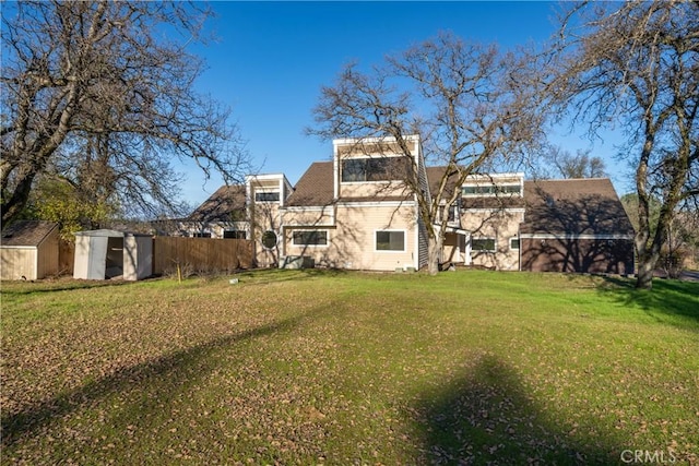 rear view of house featuring a yard and a storage shed