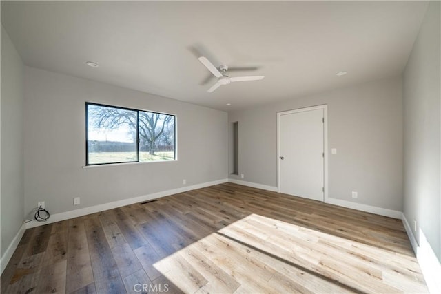 empty room with ceiling fan, baseboards, and wood finished floors