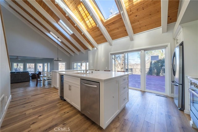 kitchen featuring sink, white cabinets, stainless steel appliances, and an island with sink