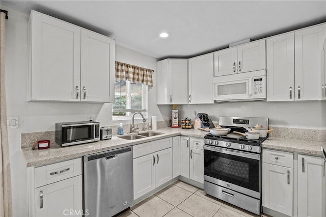 kitchen featuring light tile patterned floors, appliances with stainless steel finishes, white cabinets, and sink