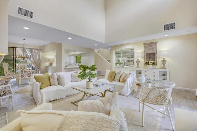 living room featuring light hardwood / wood-style floors, a high ceiling, and a chandelier