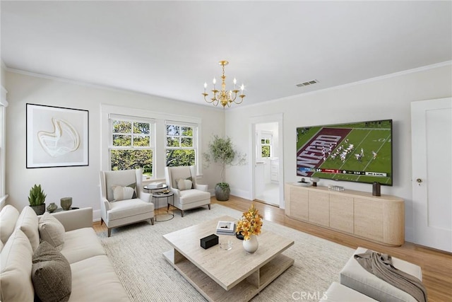 living room with light wood-type flooring, ornamental molding, and an inviting chandelier